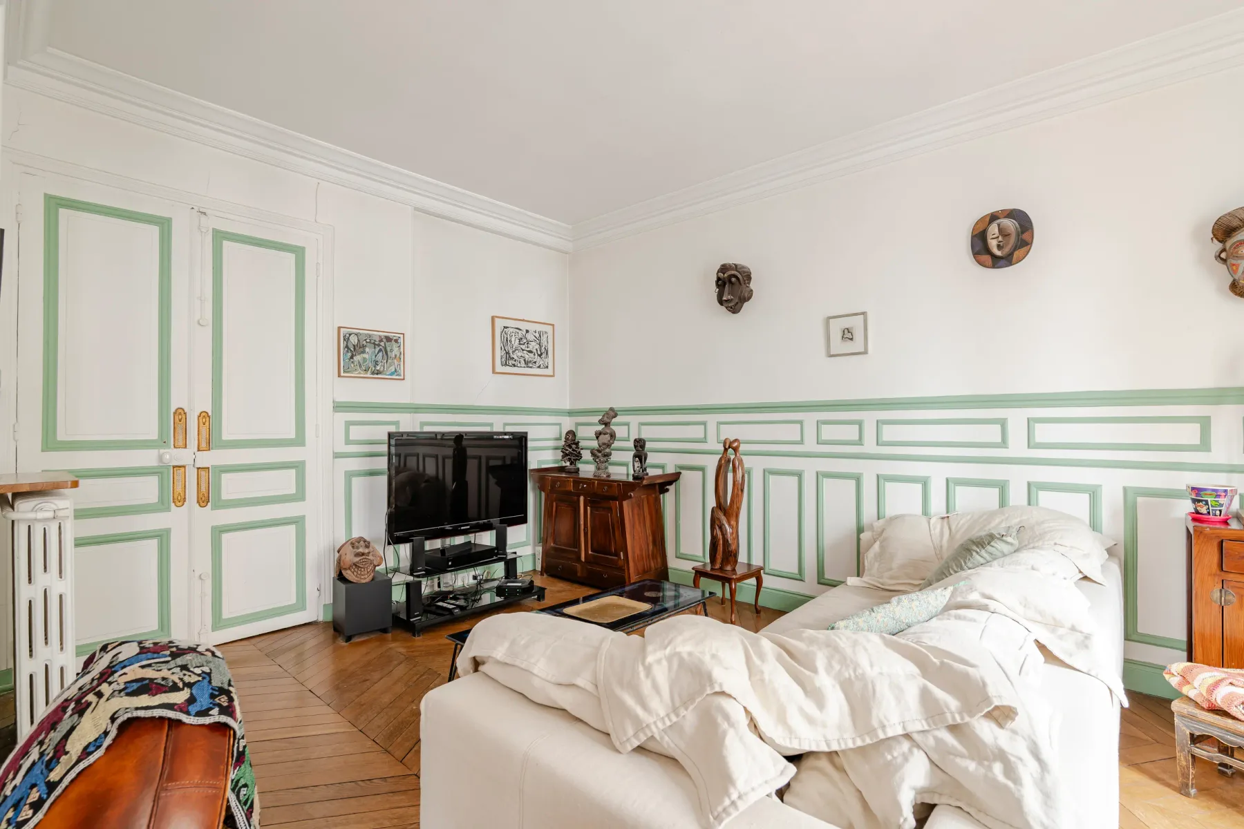 A bedroom with an unmade bed, television, and green-trimmed walls.