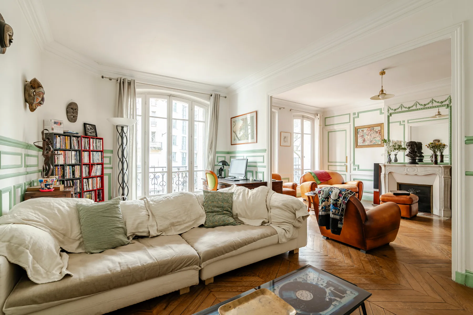 A bright living room with cream seating, a bookcase, and a fireplace.