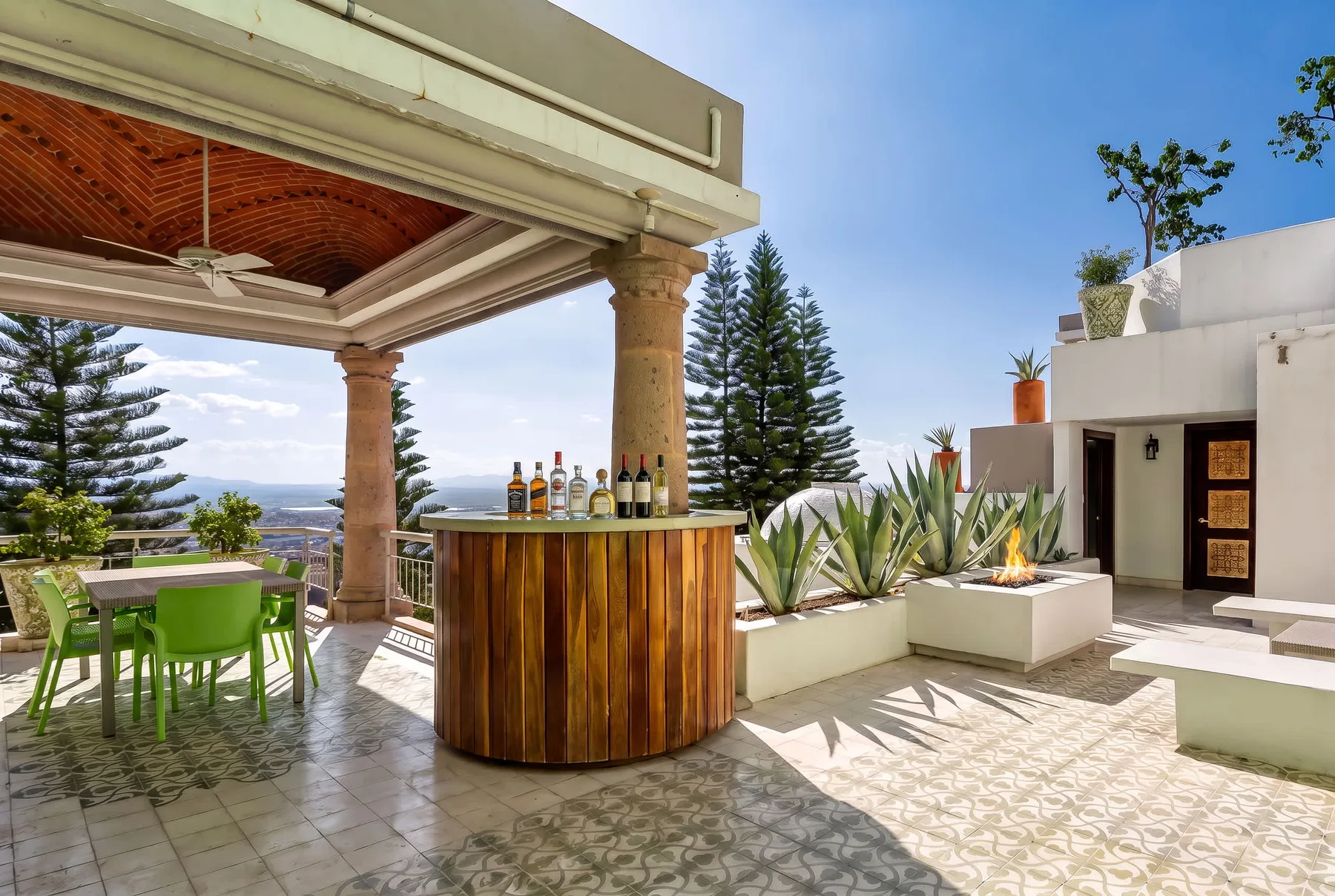 Un patio exterior cuenta con una barra redonda, una mesa de comedor y una pequeña chimenea.