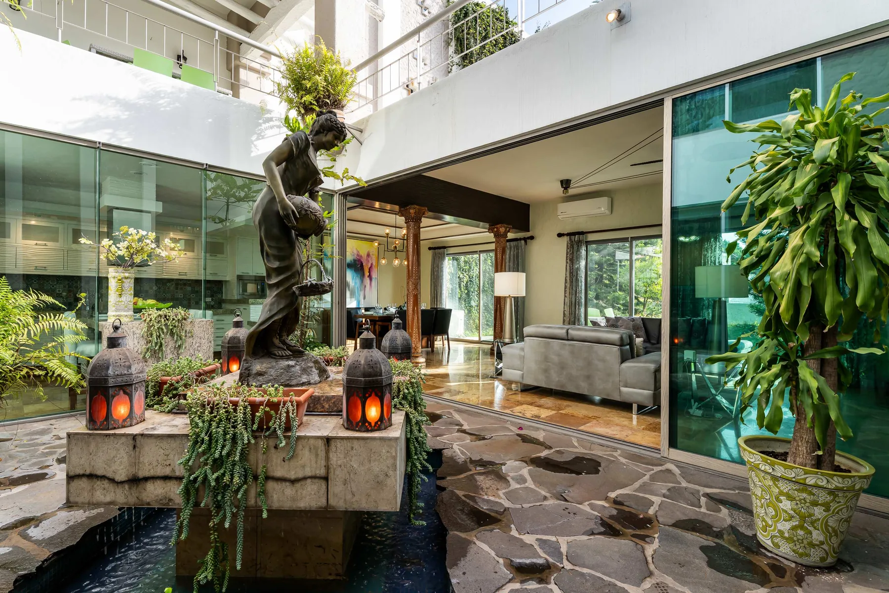 Un patio interior abierto con una fuente, pavimento de piedra y asientos.