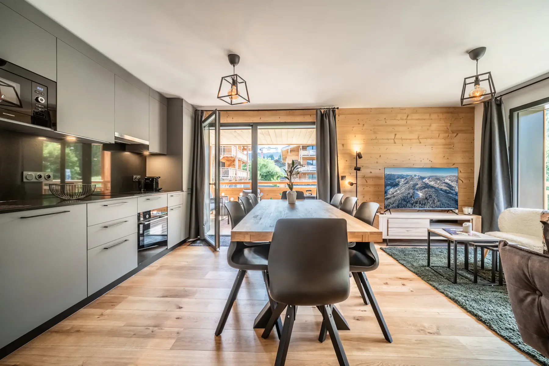 Una cocina abierta con comedor y una mesa junto a grandes ventanas.