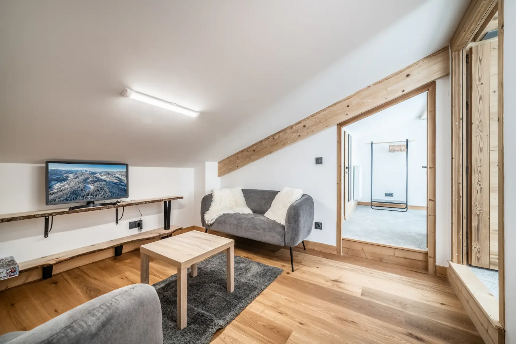 Una sala de estar con televisor, asientos y una mesa de centro de madera.
