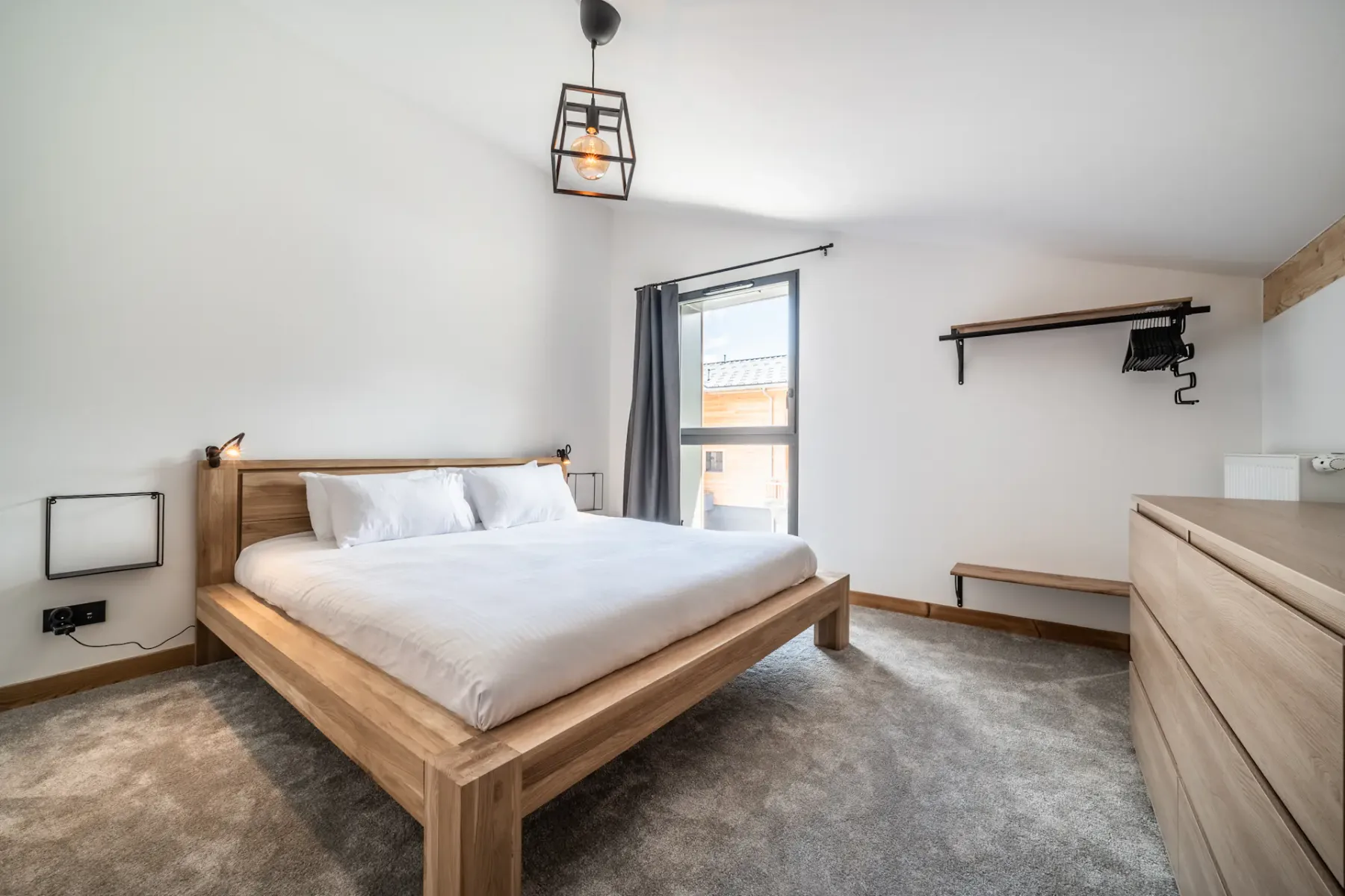 Un dormitorio con una cama de madera, ropa de cama blanca y una ventana.