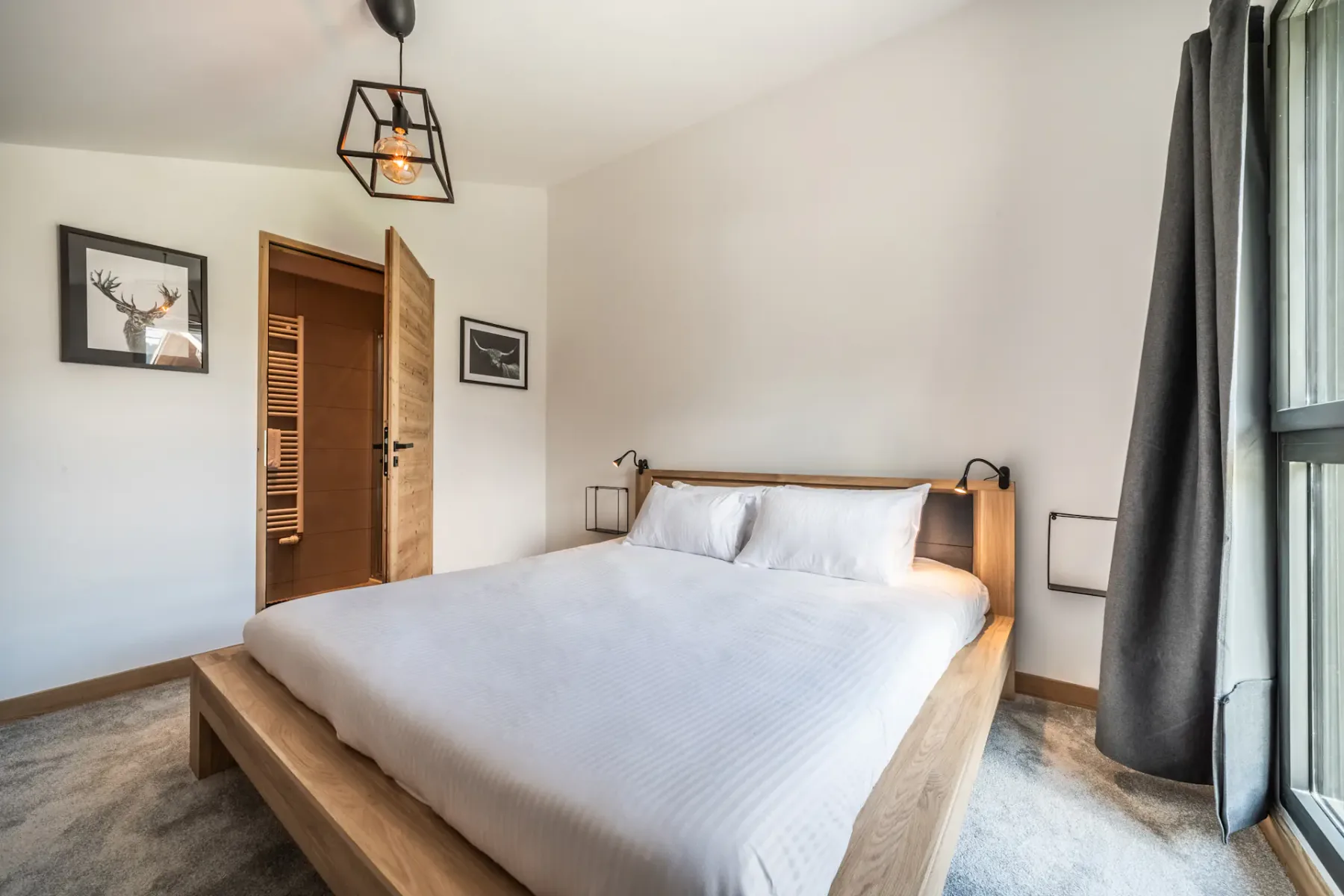 Dormitorio con una cama, cuadros enmarcados y una ventana grande.