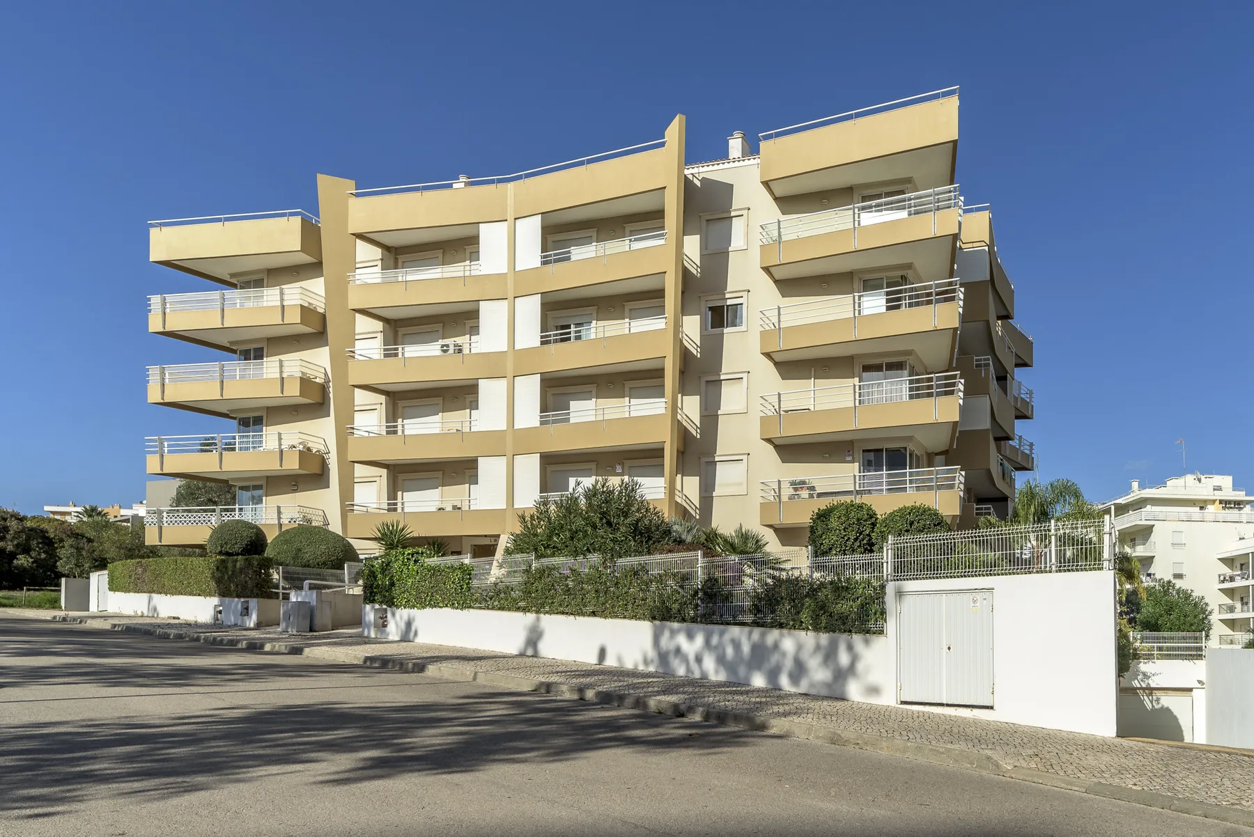 Un edificio de apartamentos moderno con balcones curvos junto a una calle.