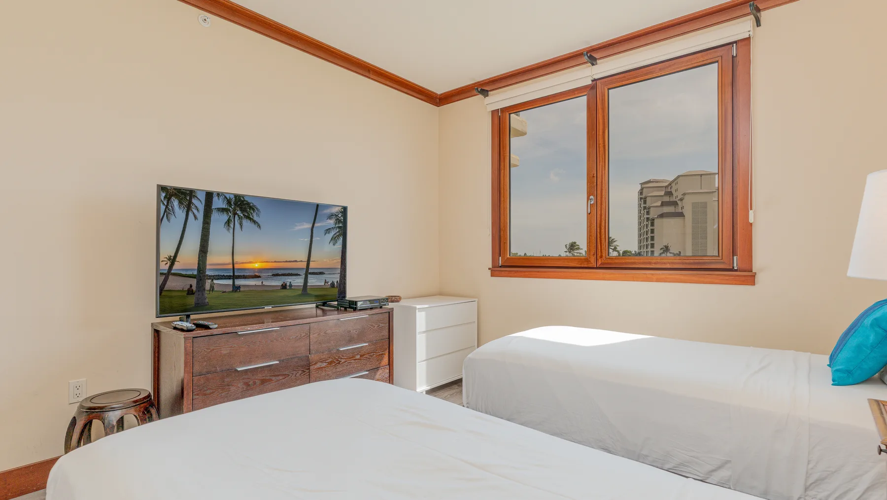 A bedroom with two beds, a television, and a window.