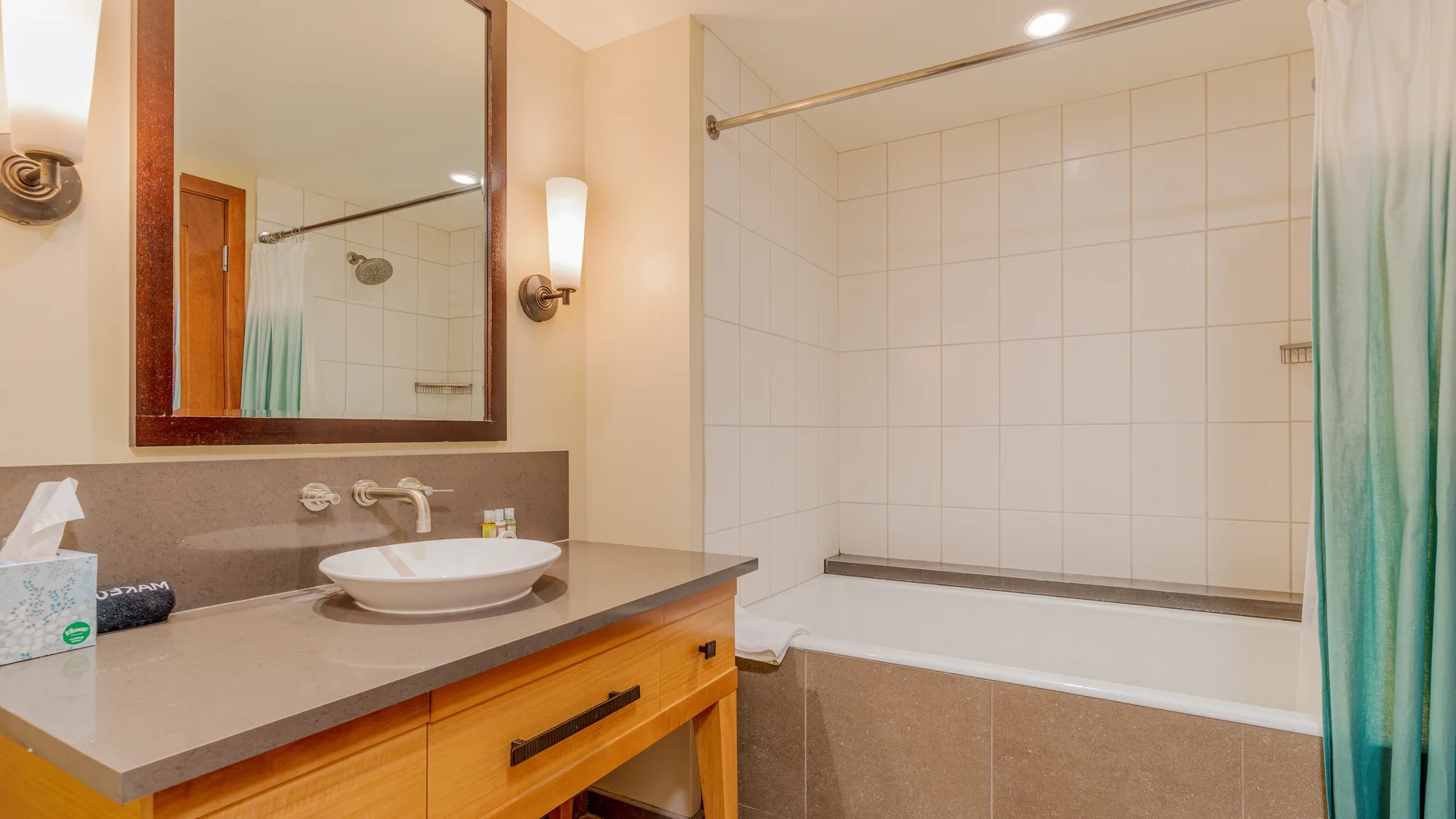 A bathroom with a sink vanity, large mirror, and bathtub with a shower curtain.