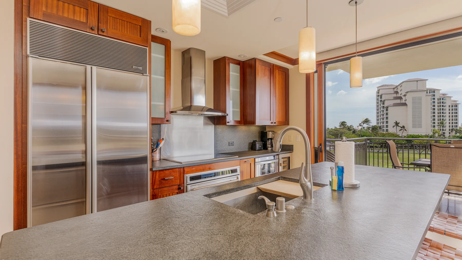 Una cocina moderna con una isla grande y ventanas con vista a edificios cercanos.