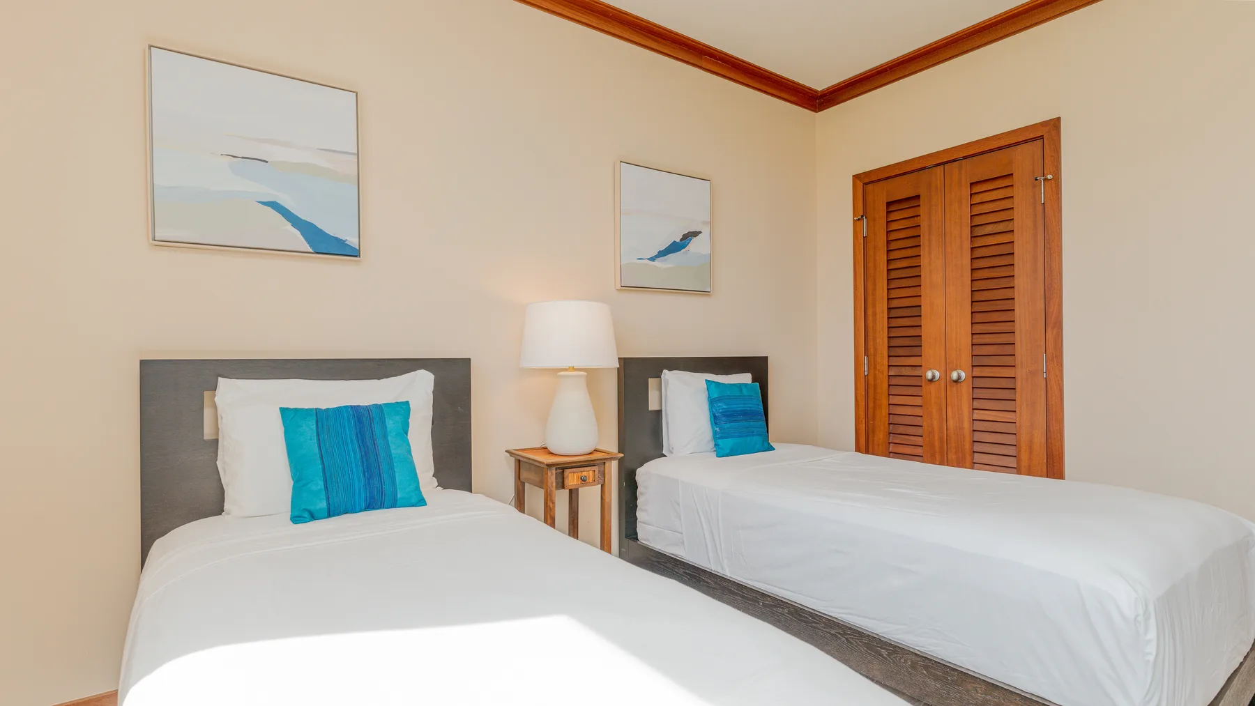 A bedroom with two neatly made beds and framed artwork on the walls.