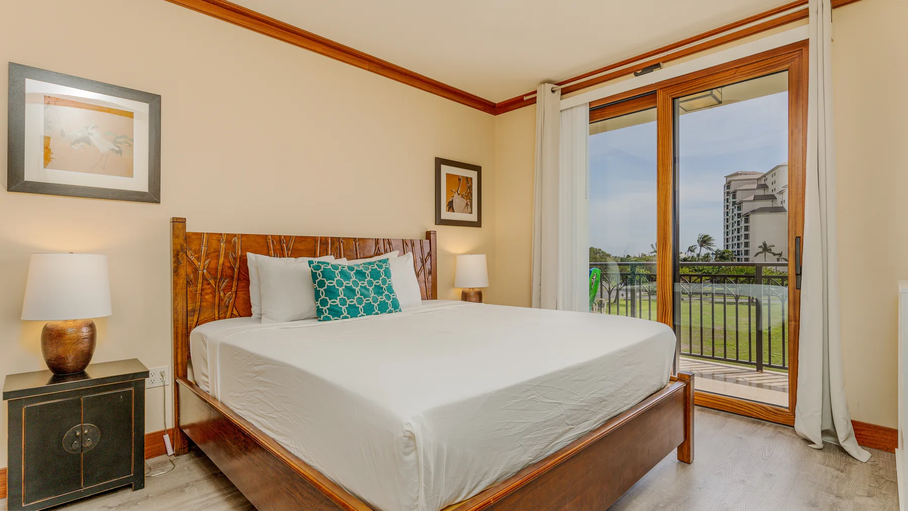 A bedroom with a neatly made bed beside a glass door opening to a balcony.