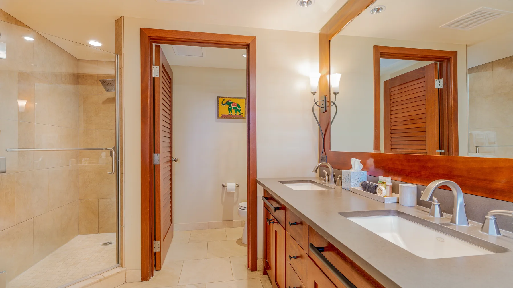 A bathroom with a glass shower, a long vanity, and a mirror.