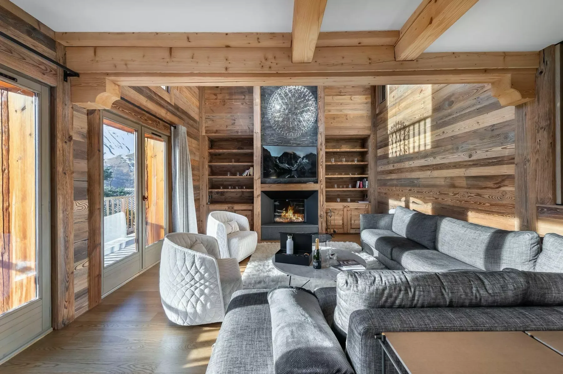 Una sala de estar revestida de madera, con asientos grises y una chimenea central.