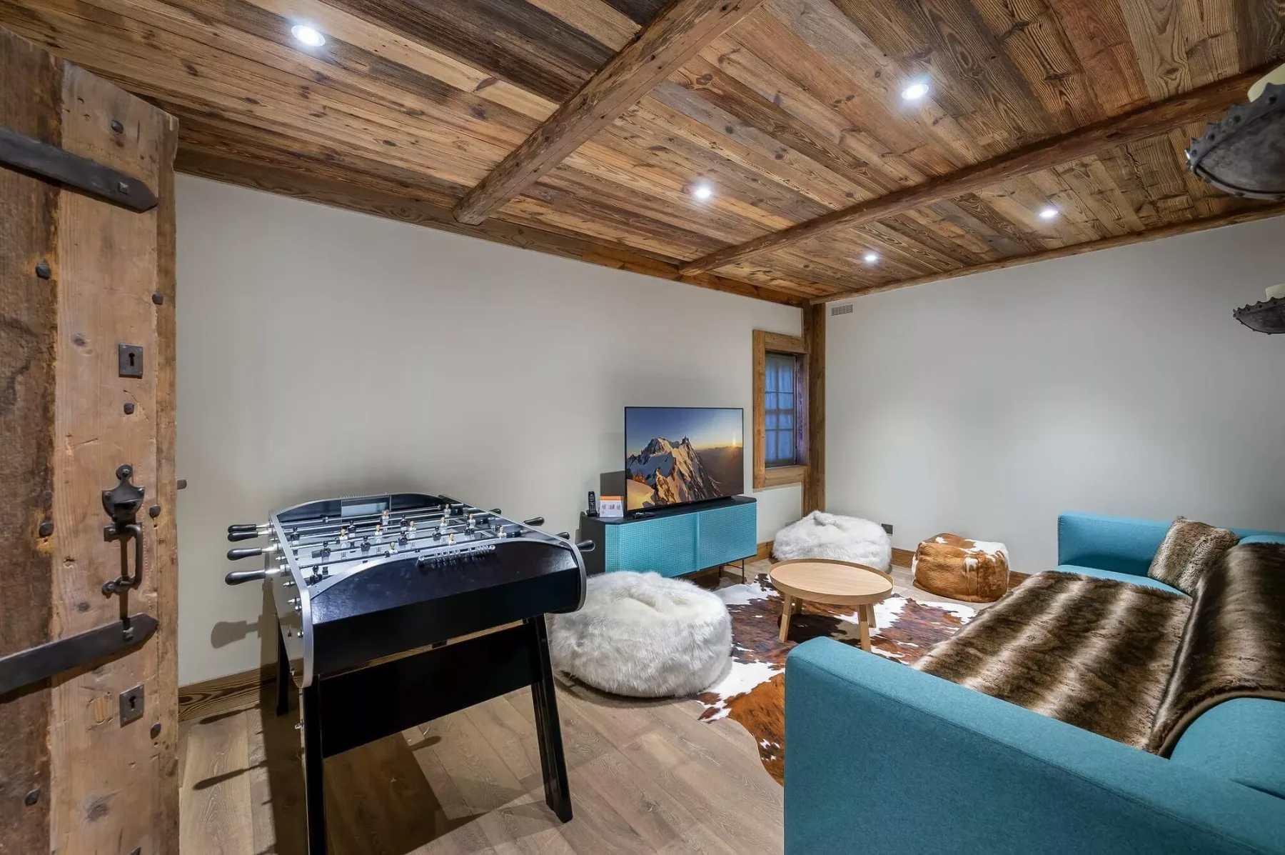 A rustic game room with a foosball table, seating, and a television.