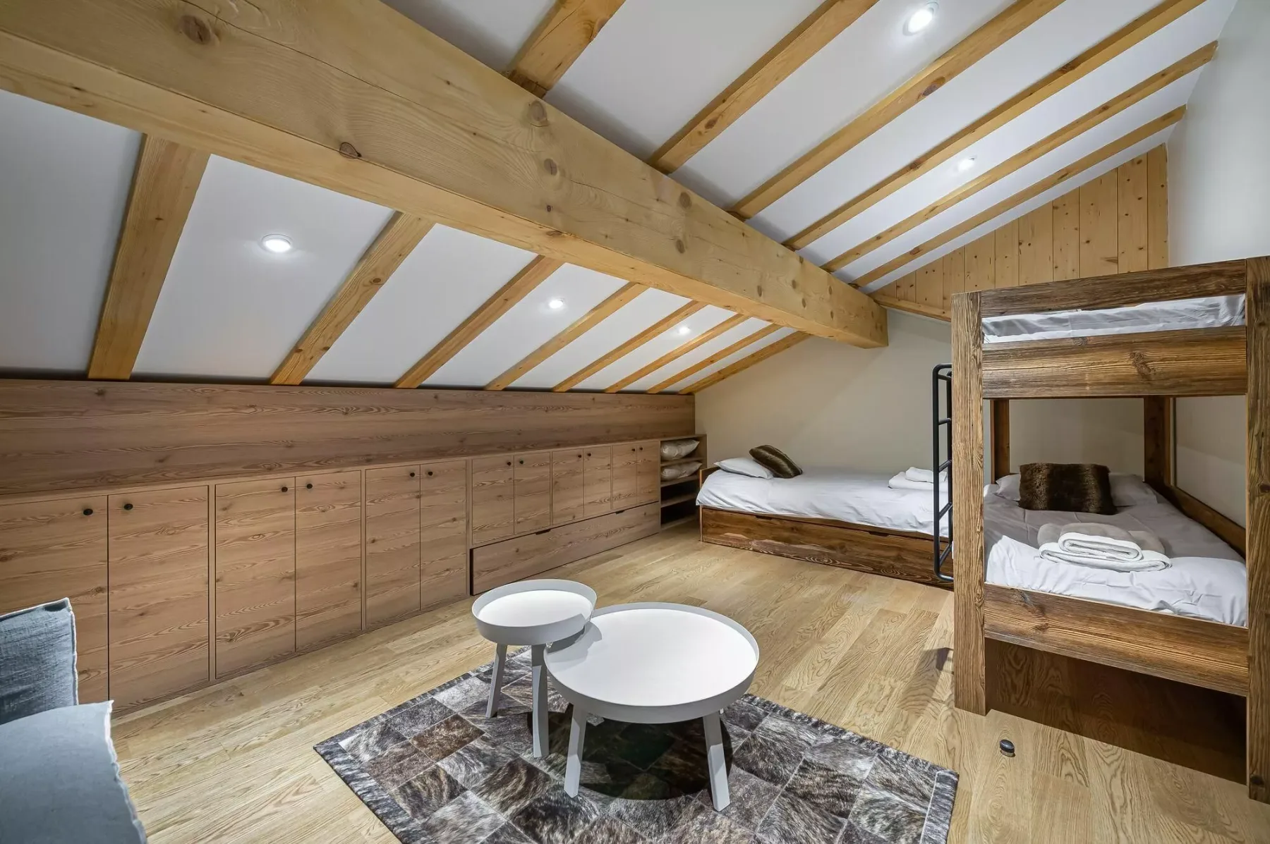 A wood-paneled loft bedroom with bunk beds and a small table.