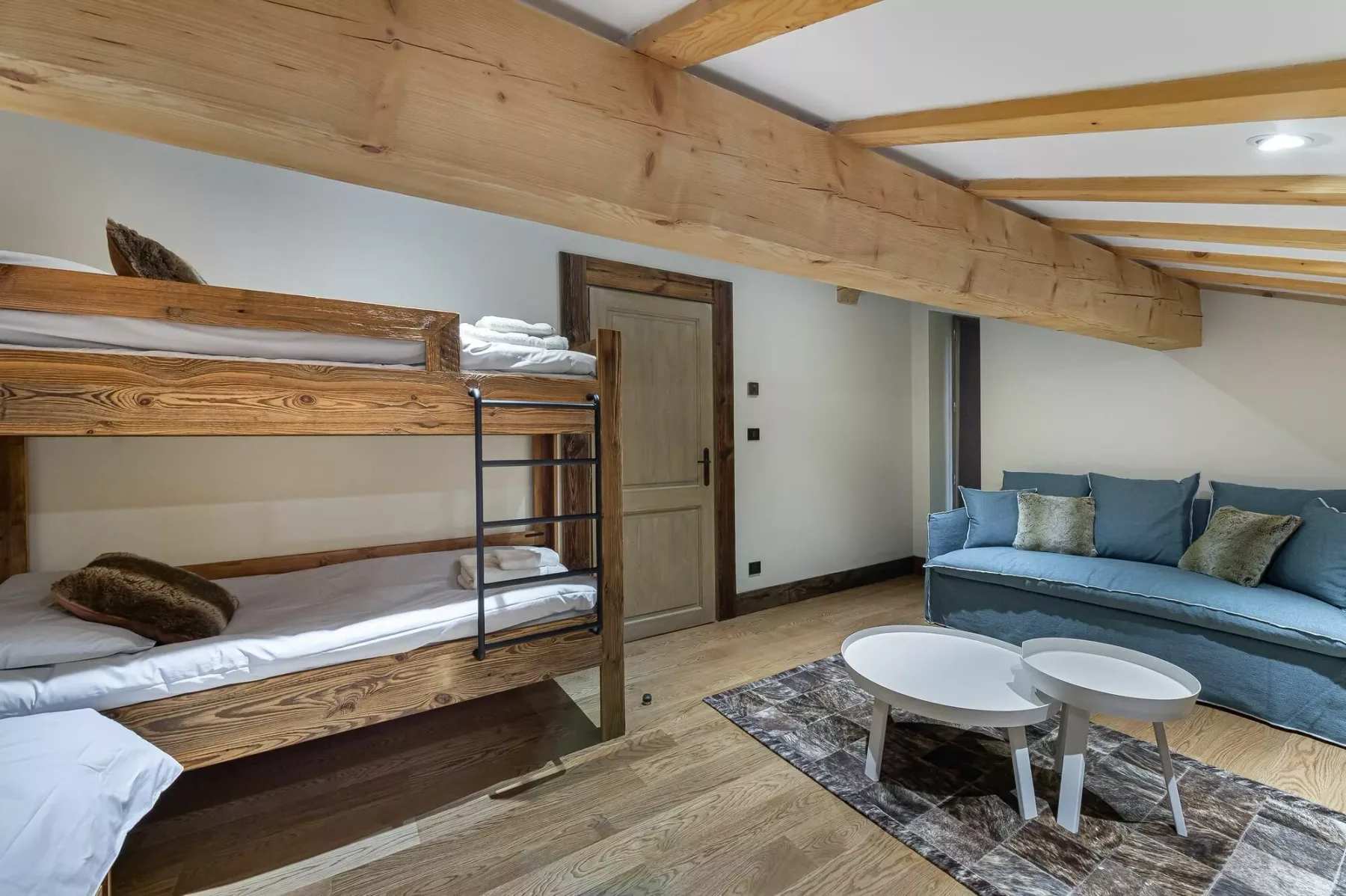 A bedroom with wooden bunk beds and a blue seating area.