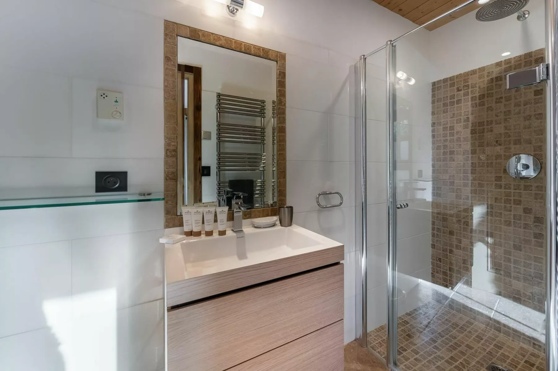 A bathroom with a sink vanity and a glass-enclosed shower.