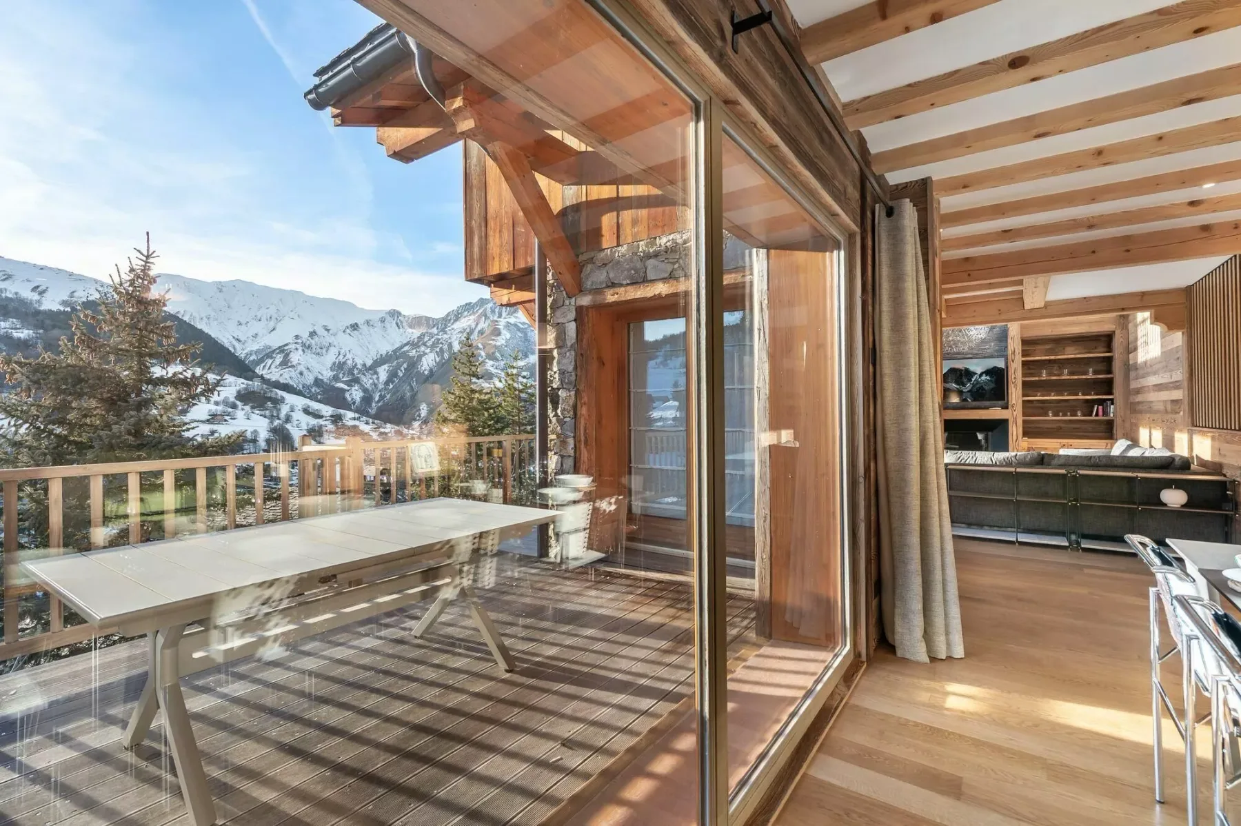 Una sala revestida de madera se abre a un balcón con vistas a las montañas.