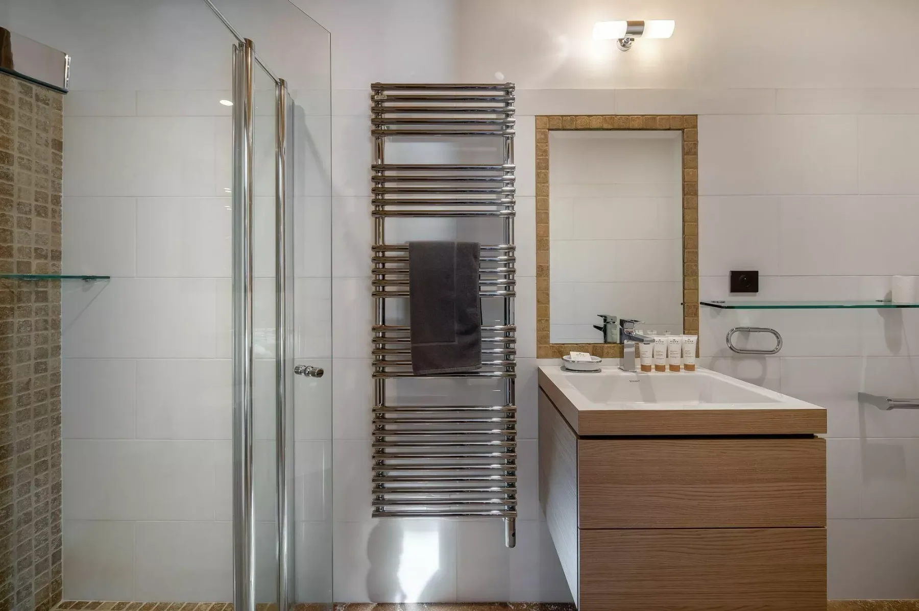 A tiled bathroom with a glass shower, vanity, and wall-mounted towel rack.