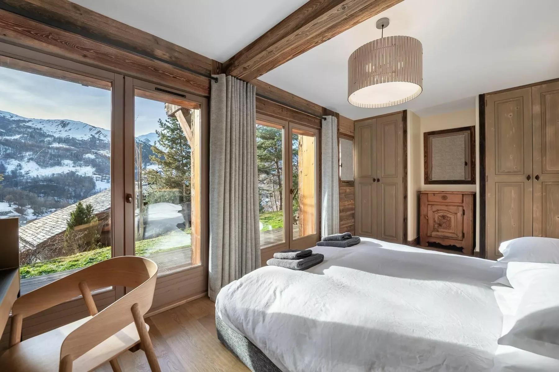 A bedroom with a large bed beside windows overlooking a mountain landscape.