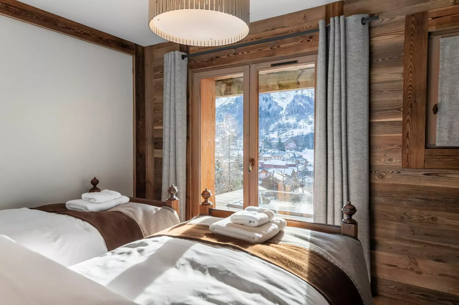 A bedroom with beds beside glass doors overlooking a snowy mountain landscape.