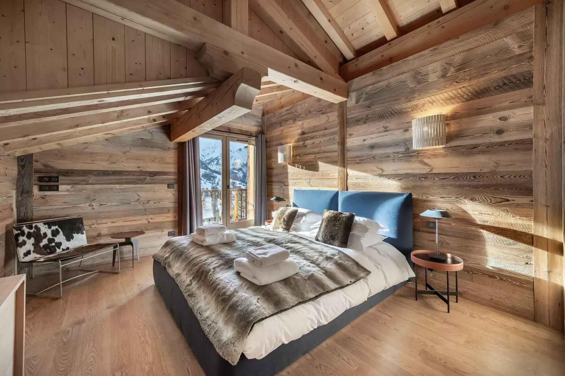 A wood-paneled bedroom with a bed beside a large window.