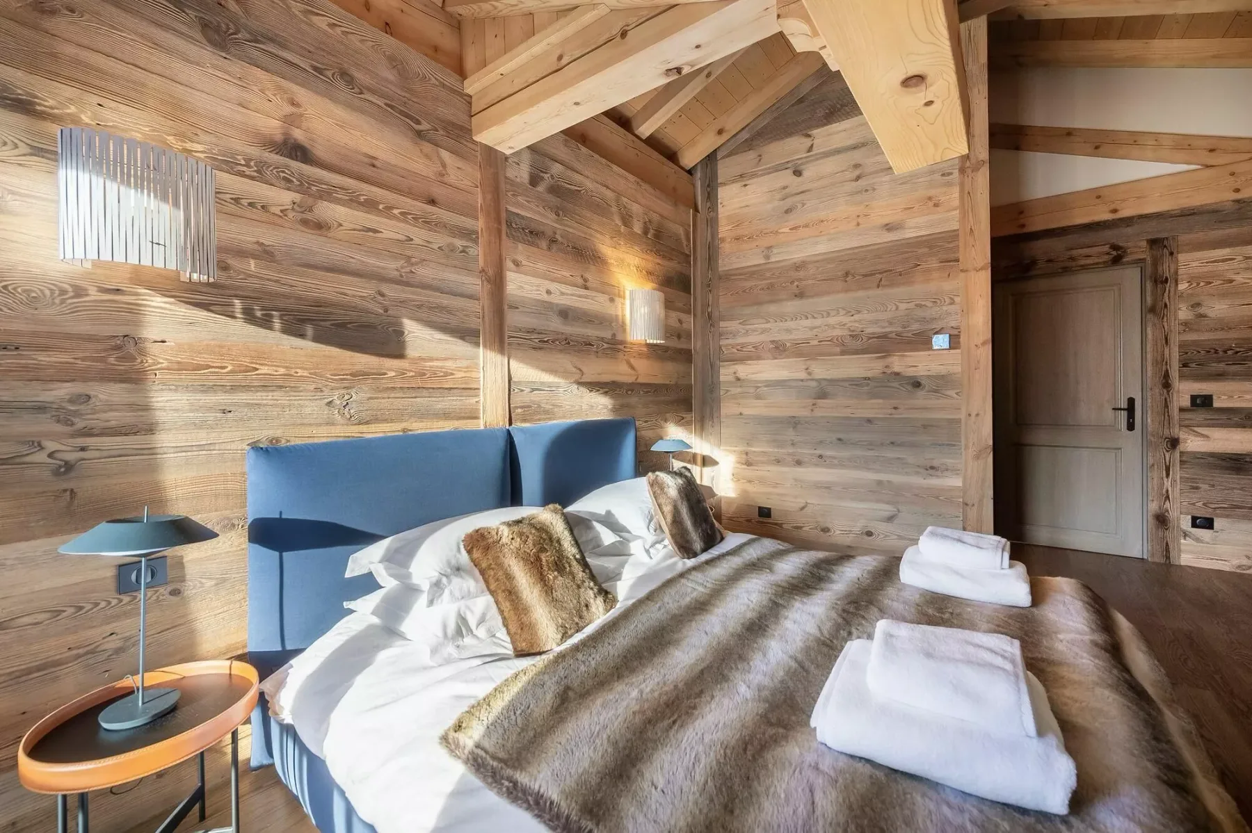 A bedroom with a bed, white bedding, and exposed wooden beams.