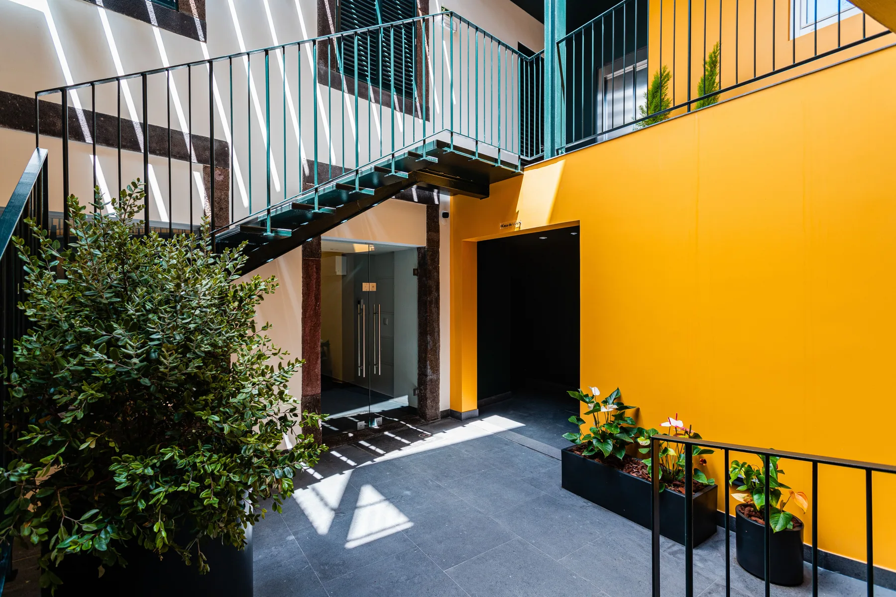 An indoor courtyard with a staircase, railings, and potted plants.