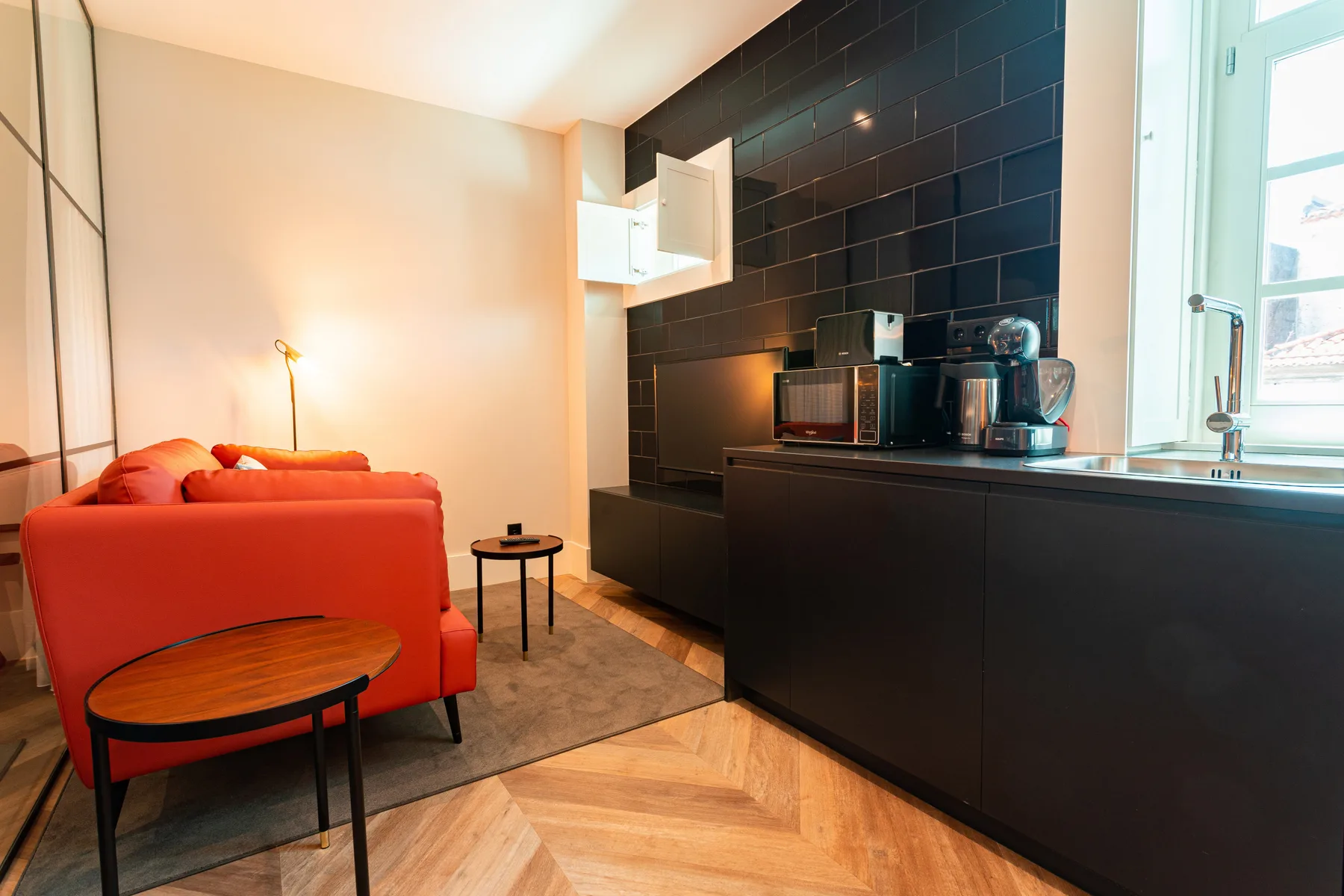 A living area with red seating beside a dark kitchen counter.