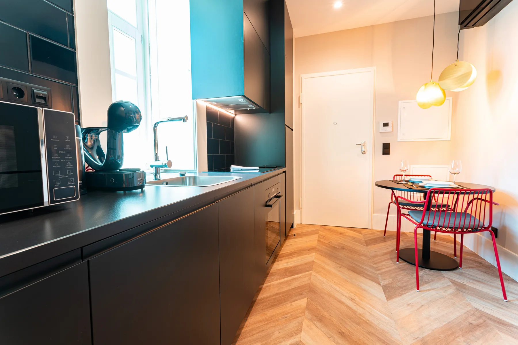 A modern kitchen and dining area with dark cabinetry and a small table.