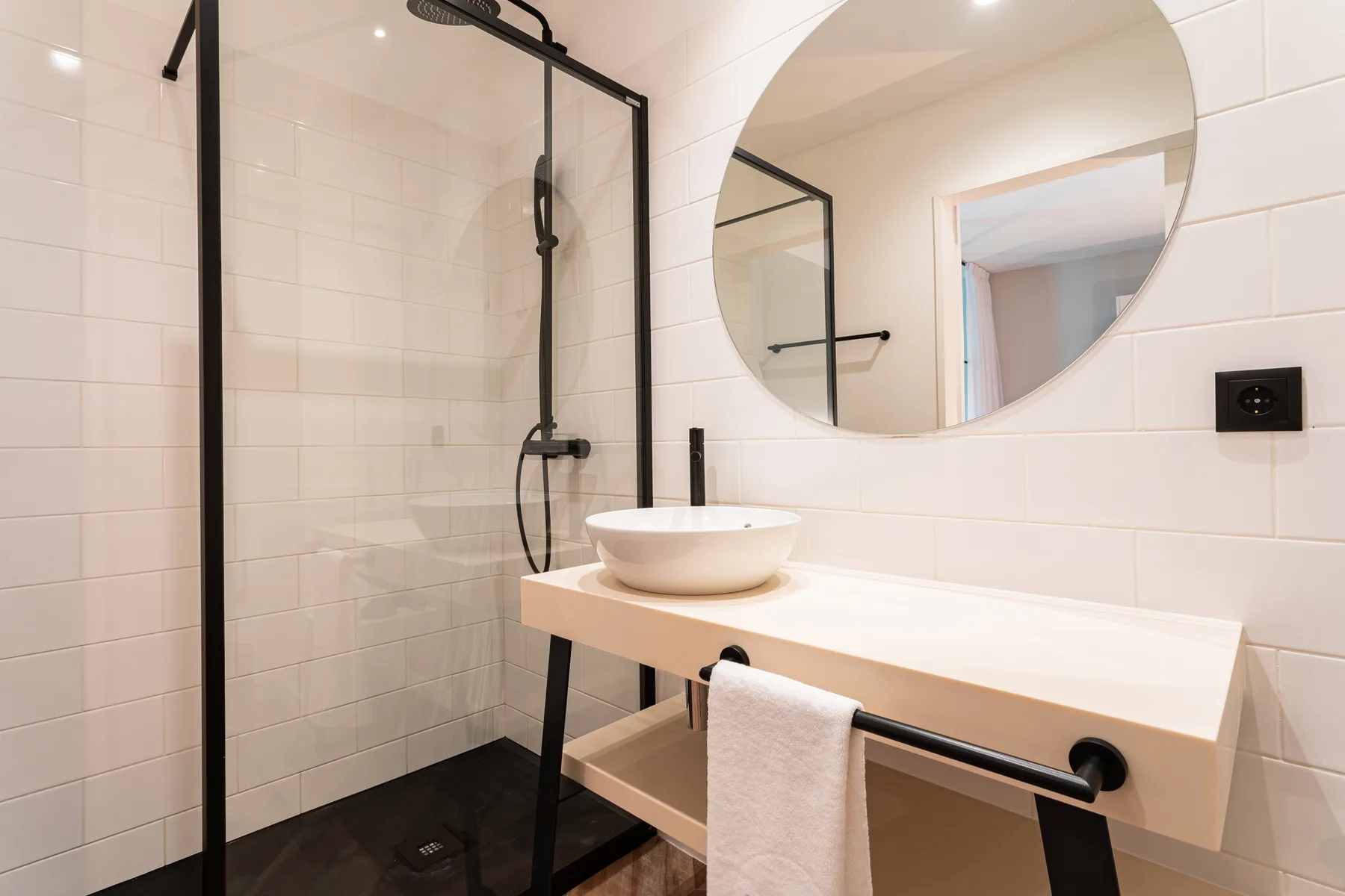 A tiled bathroom with a glass shower and a white sink vanity.