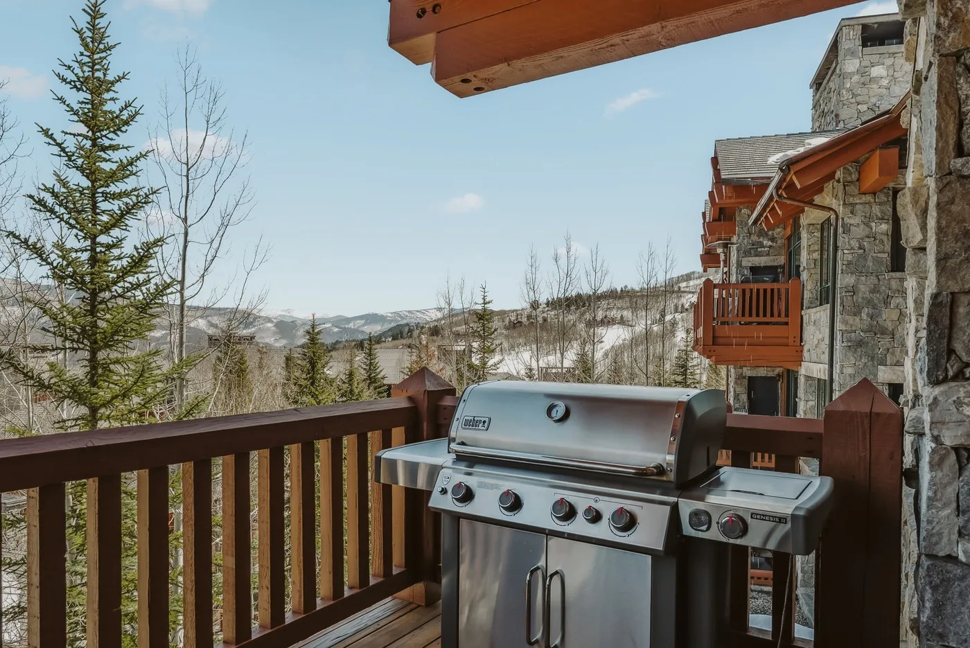 Un balcón con una parrilla mira hacia un paisaje boscoso con nieve.