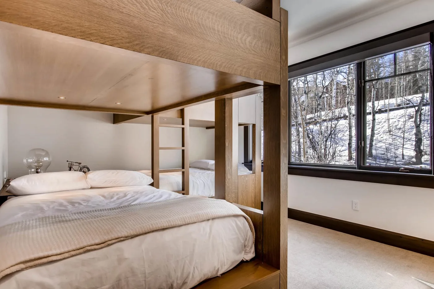Un dormitorio con una estructura de cama elevada de madera junto a una ventana grande.