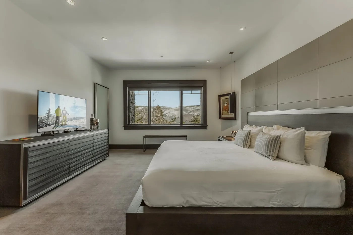 Un dormitorio con una cama grande, un televisor y una ventana amplia.