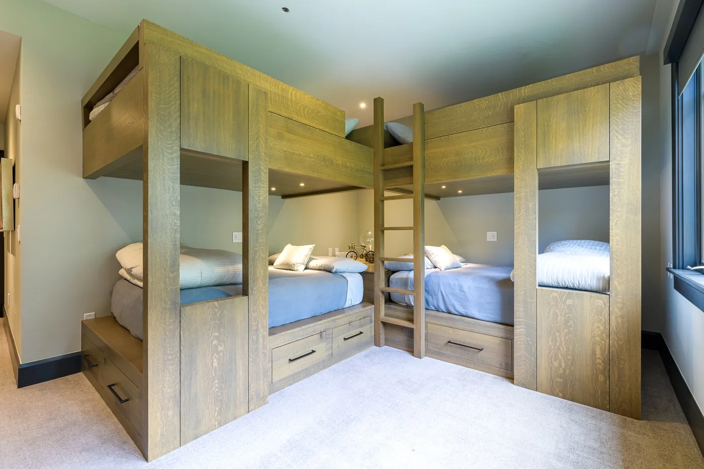 Un dormitorio con literas de madera, escaleras integradas y ropa de cama azul.