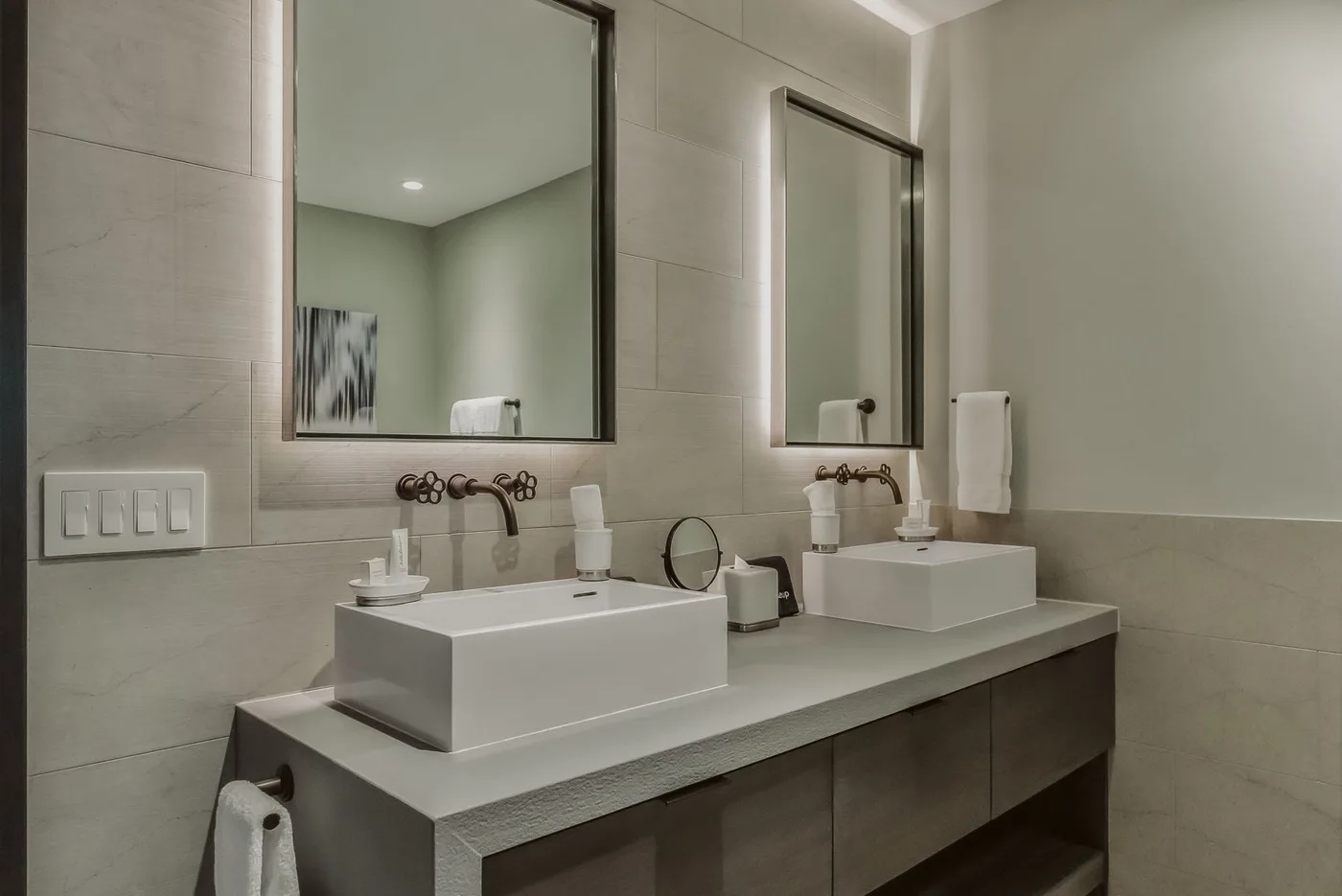 Un tocador de baño con dos lavabos, espejos y grifos de pared.