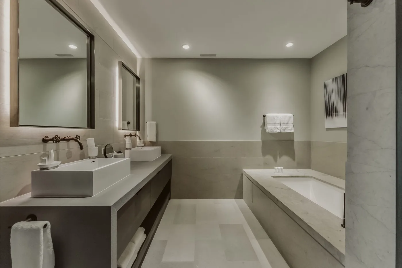 Un baño moderno con un lavabo alargado, espejo y bañera.