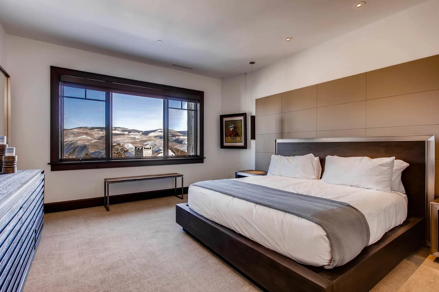 Un dormitorio con una cama grande y una amplia ventana con vistas a un paisaje montañoso.