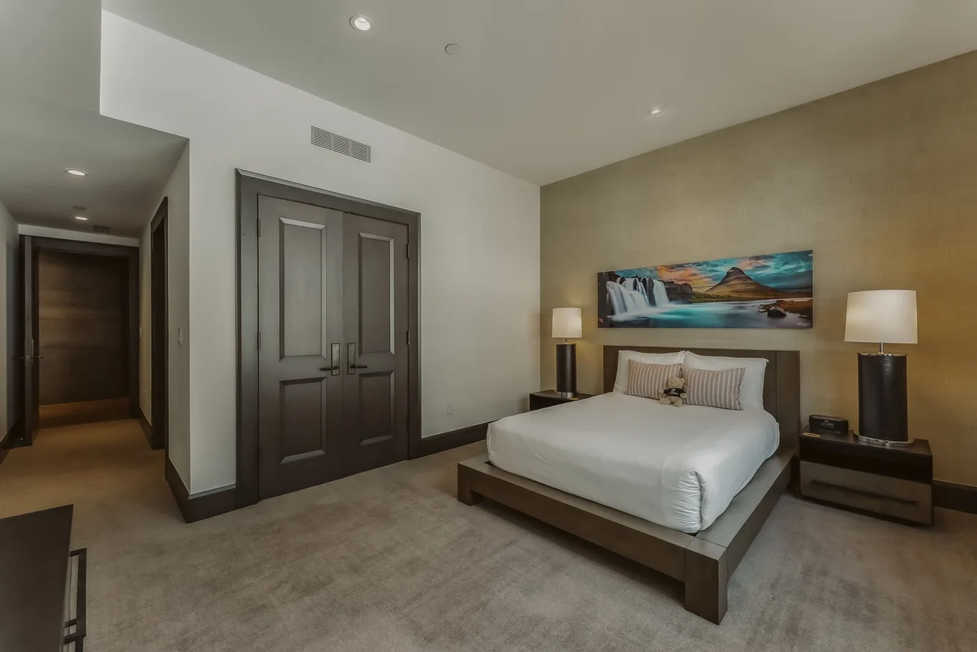 Un dormitorio con una cama bien hecha, mesitas de noche y arte colorido en la pared.