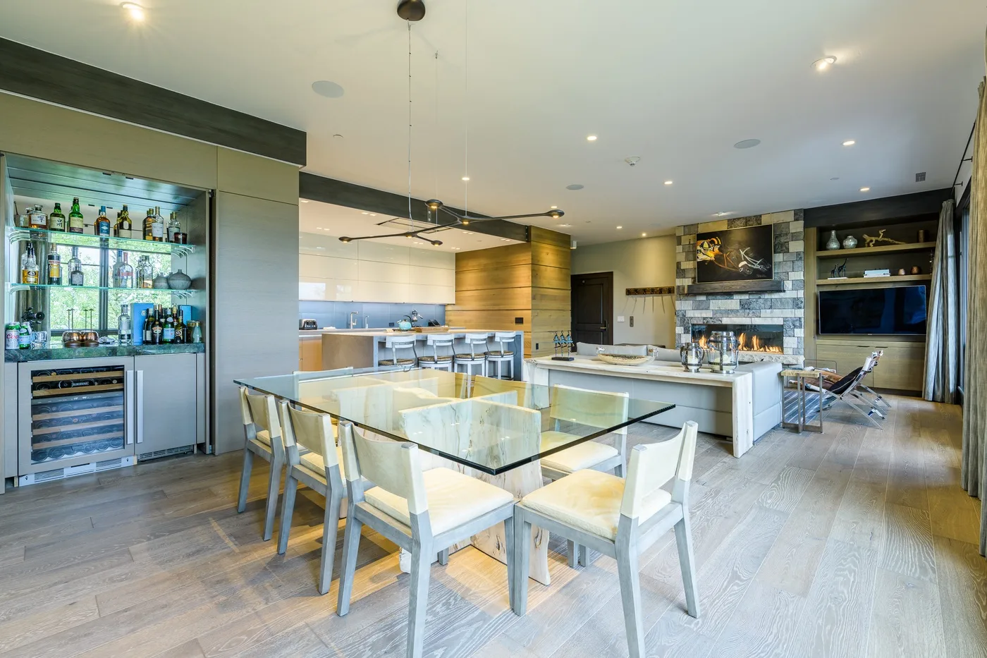 Open-plan kitchen and dining area with a glass dining table and bar counter.