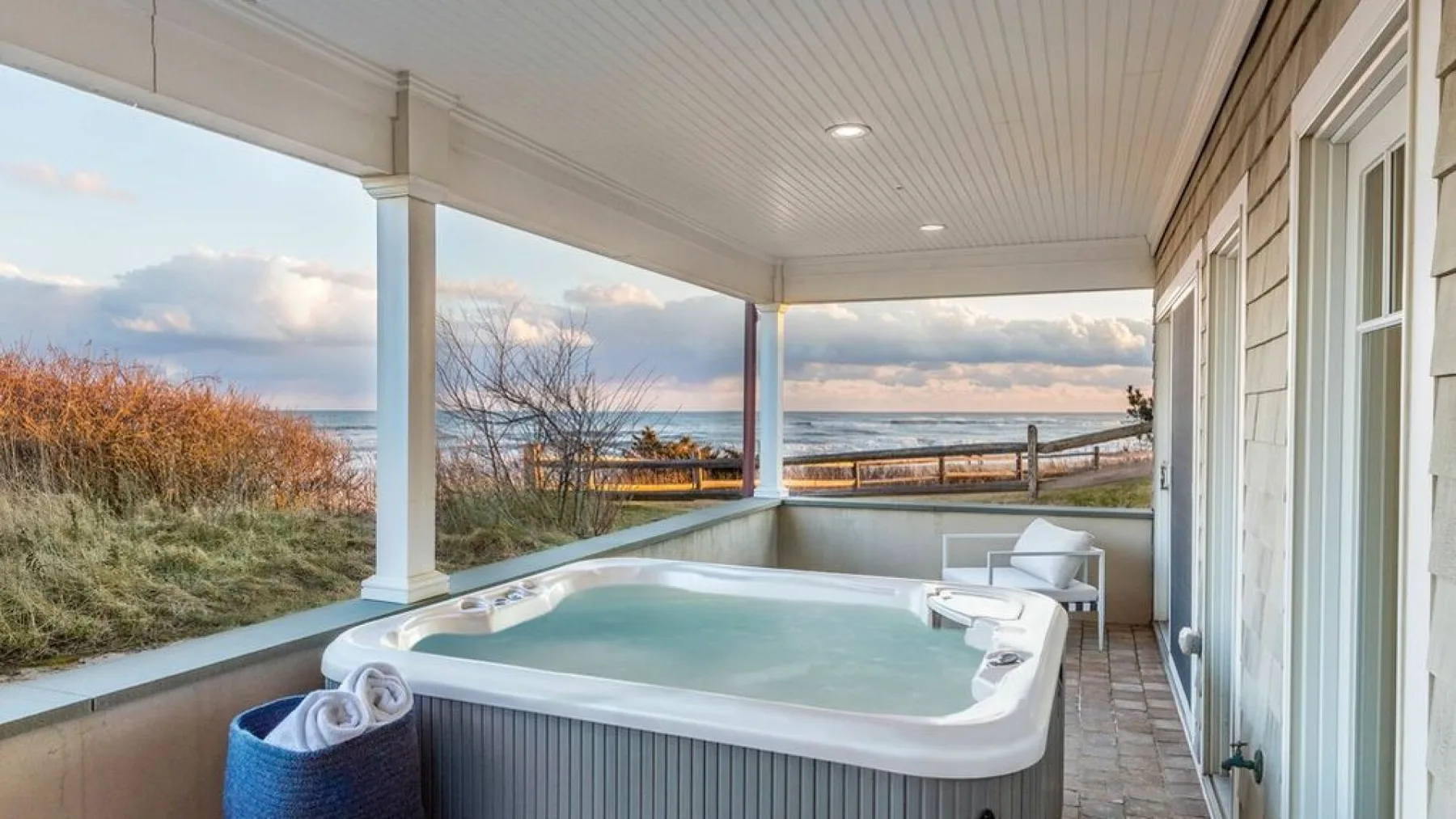 A covered porch with a hot tub overlooking the ocean.