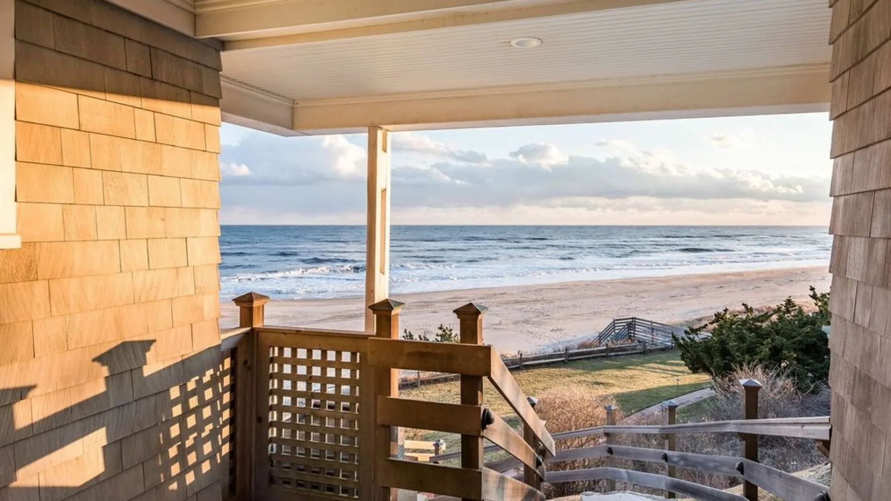 Una terraza cubierta de madera da al mar y la playa.