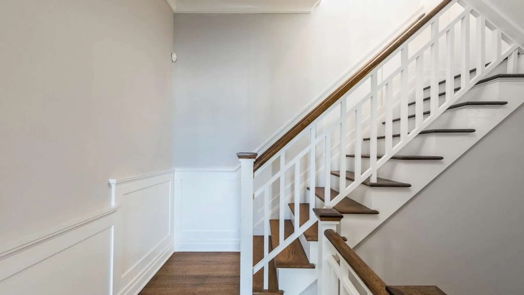 An interior staircase with white railings and wooden steps.