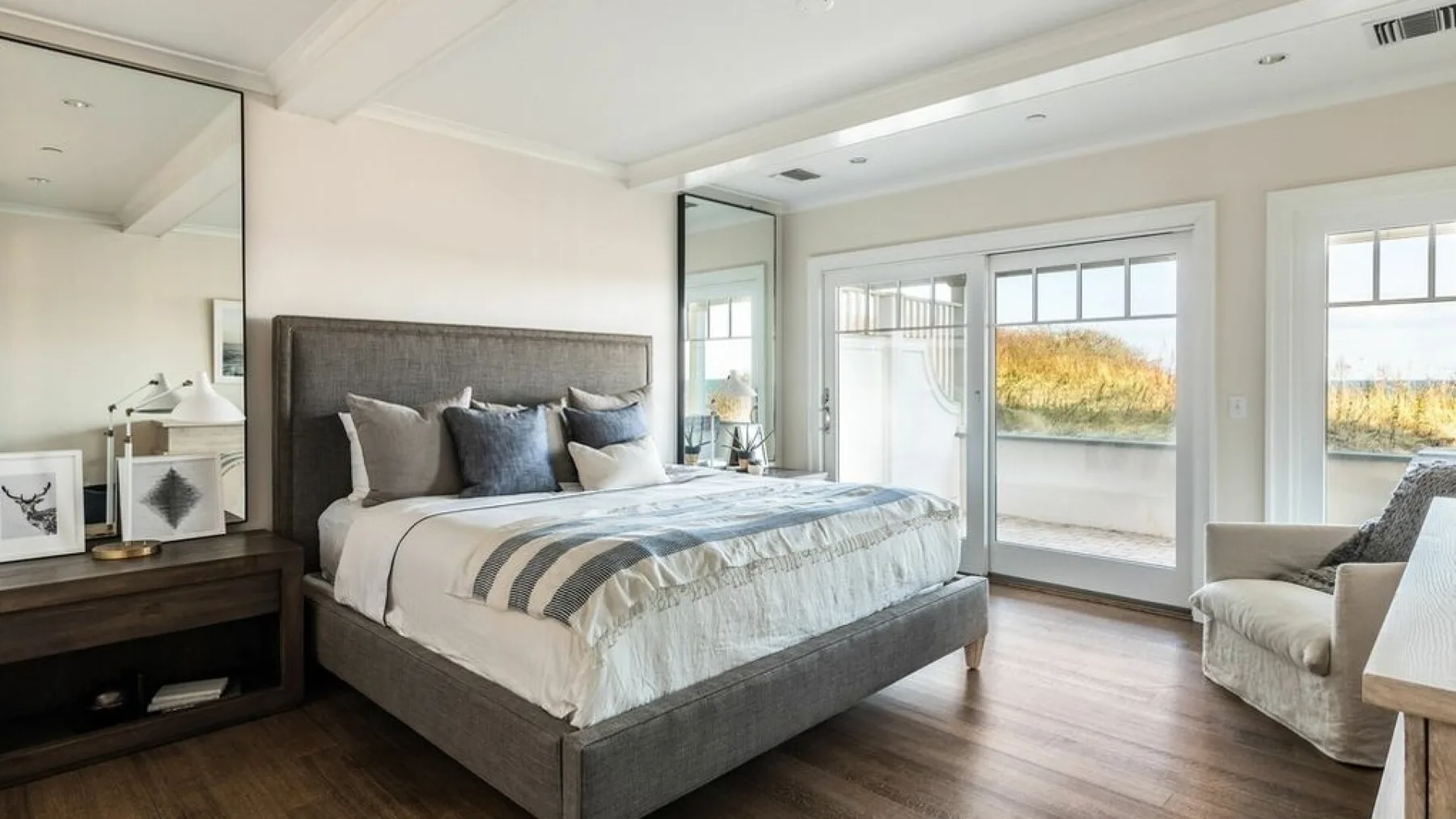 A bedroom with a large bed and windows overlooking a balcony.