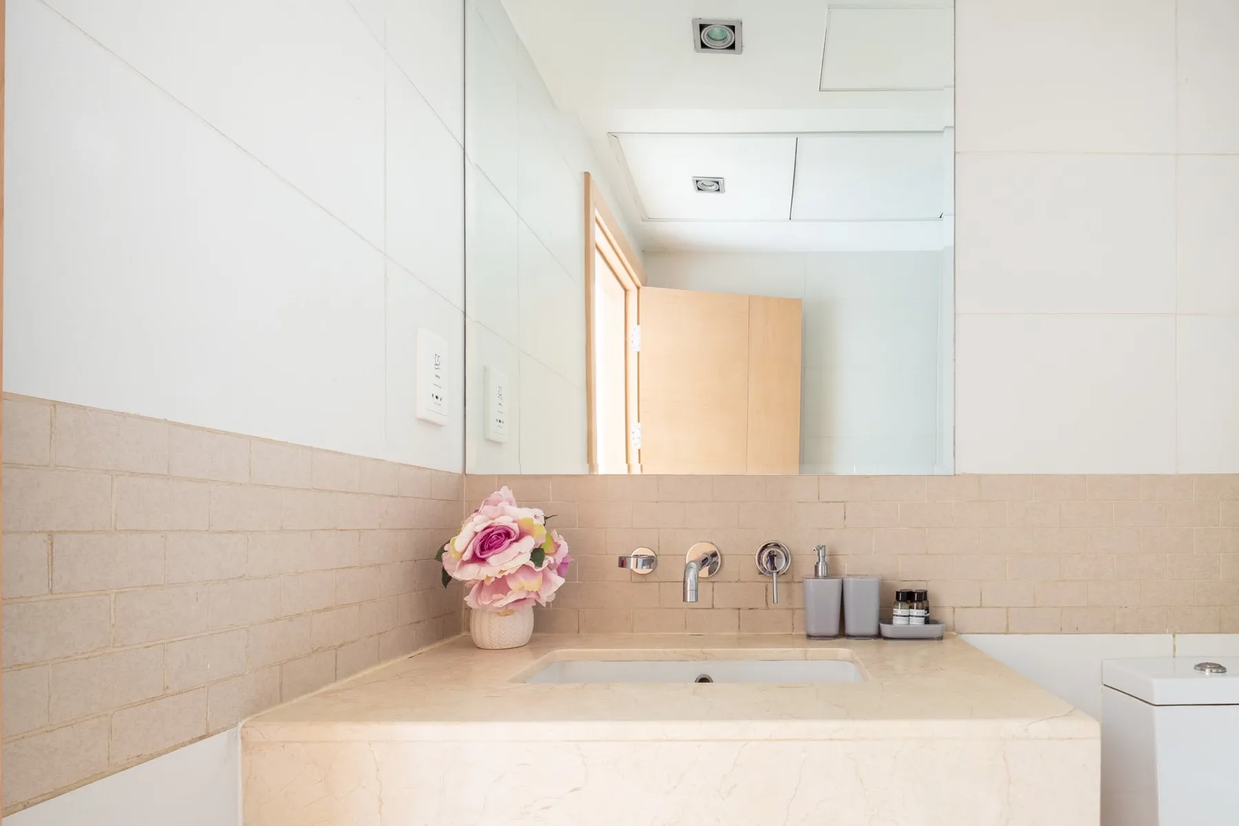 Un lavabo de baño con espejo de pared y flores.