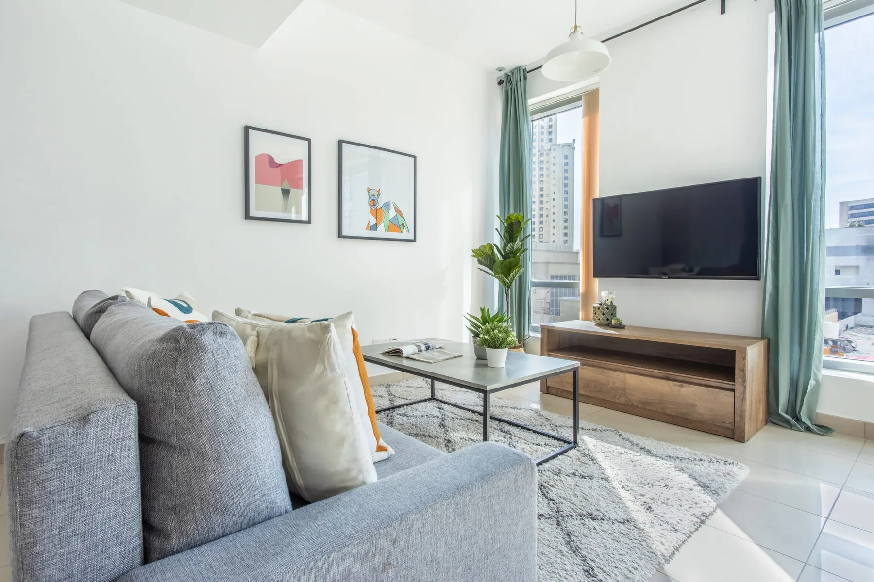 Una sala de estar luminosa con asientos, una mesa de centro y un televisor.