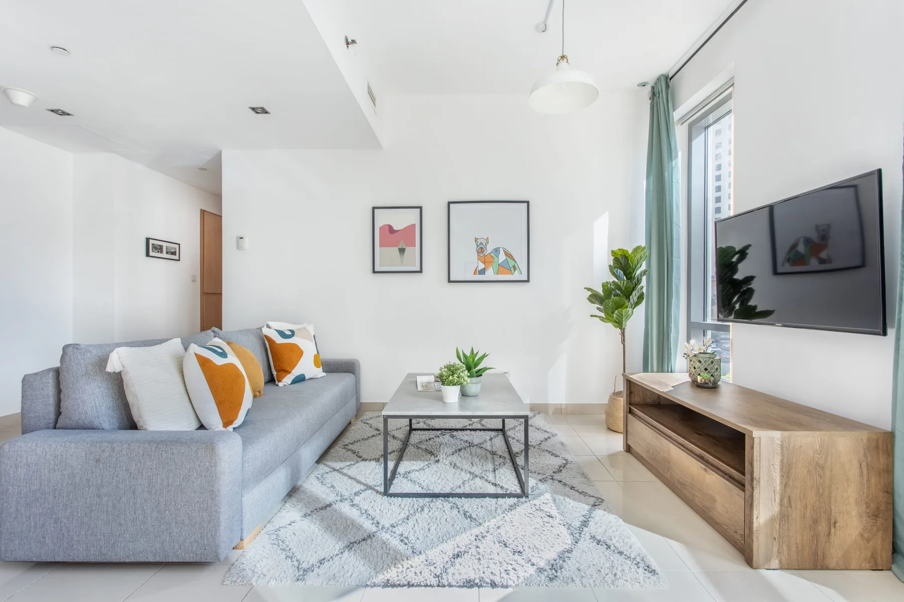 Una sala luminosa con asientos, una mesa de centro y un televisor en la pared.