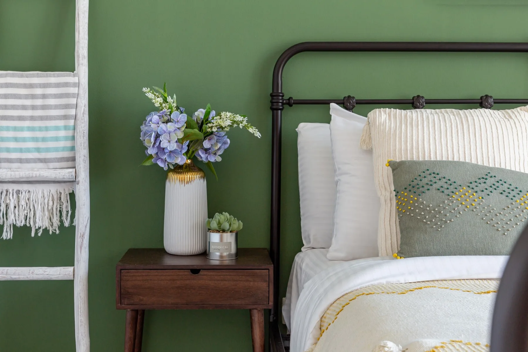 Dormitorio con una cama ordenada y una mesita de madera junto a ella.