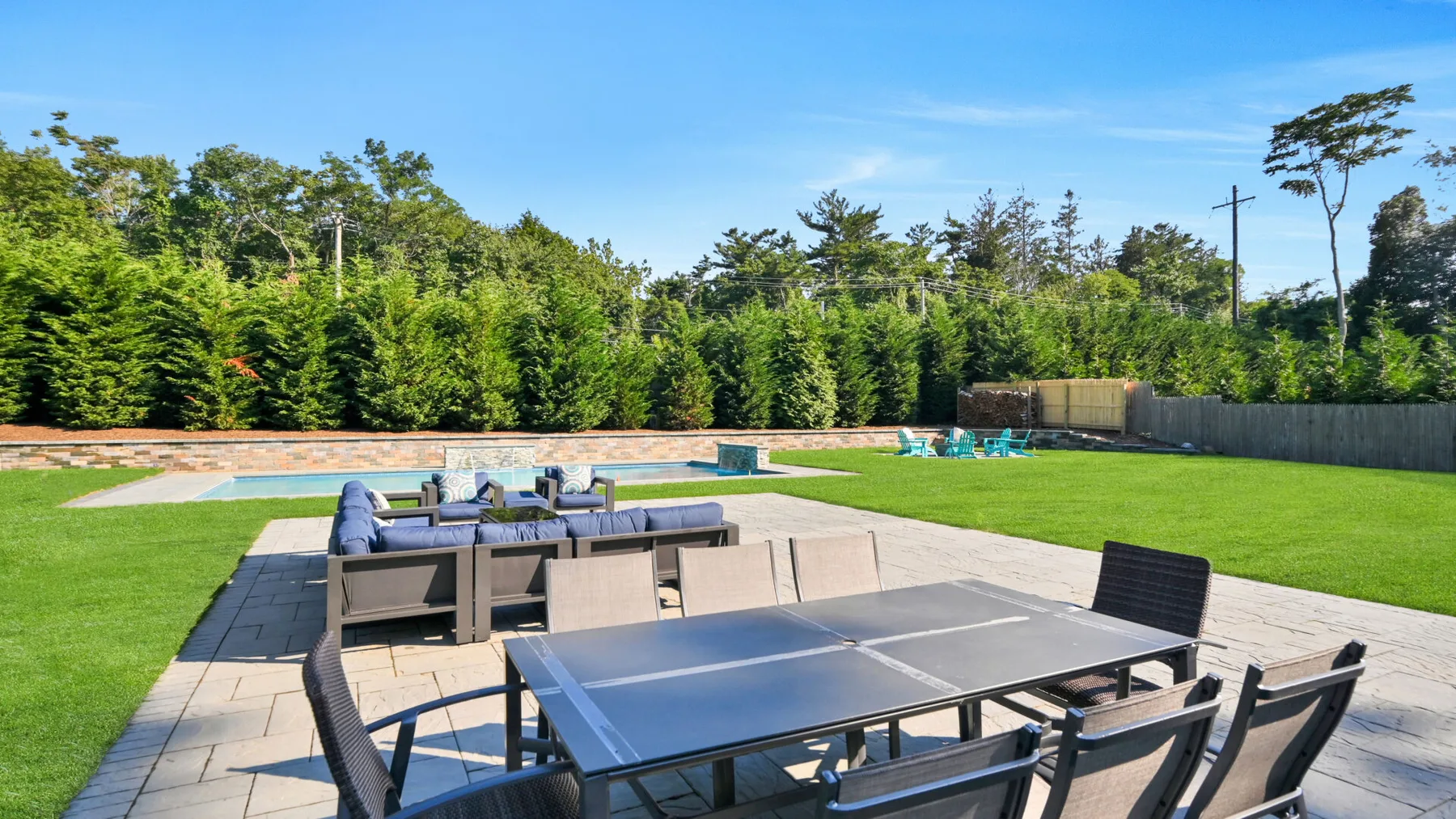 Un patio al aire libre con una mesa de ping-pong y asientos junto a un césped verde.