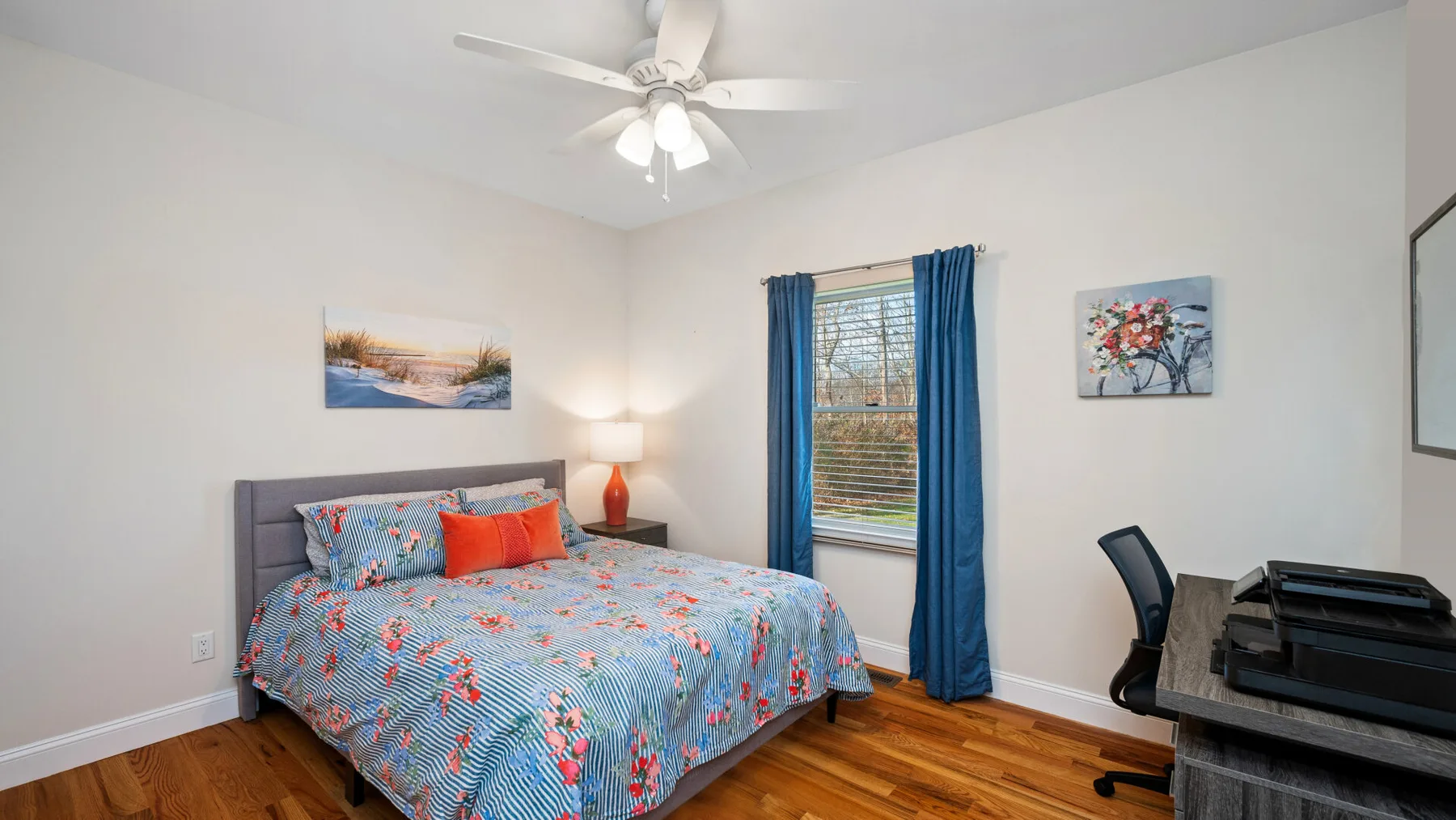 Un dormitorio con una cama, cortinas azules y un escritorio.
