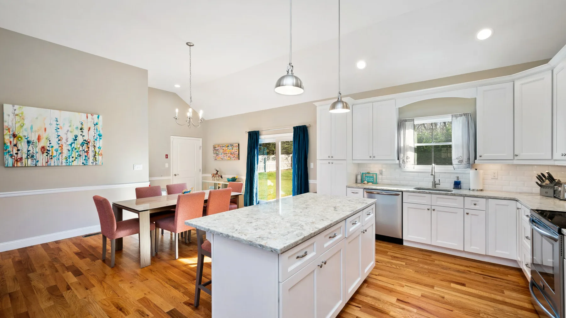 Una cocina abierta y zona de comedor con una isla central y suelo de madera.